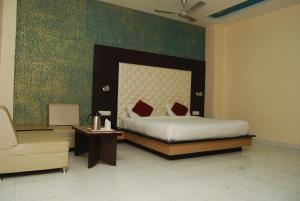 a bedroom with a large bed and a chair at Hotel Vishnu Vilas in Rewa