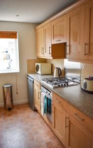 a kitchen with wooden cabinets and a stove top oven at Welcome Home in Royston