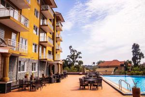 a hotel patio with tables and chairs next to a swimming pool at Hotel Duomo and Suites in Kampala