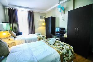 una camera d'albergo con due letti e una televisione di The Studio 87 Residences a Manila