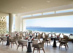 a restaurant with tables and chairs and a view of the ocean at Mayia Exclusive Resort & Spa - Adults Only in Kiotari