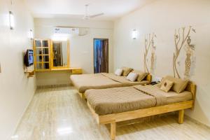 a bedroom with two beds and a tv in it at Rathna Square in Pollāchi