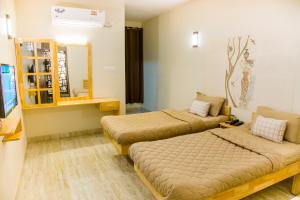 a hotel room with two beds and a mirror at Rathna Square in Pollāchi
