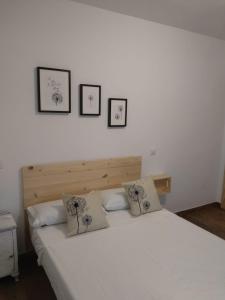 1 dormitorio con 1 cama blanca y 3 cuadros en la pared en Apartamentos Ciempozuelos, en Ciempozuelos