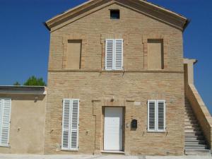 un vecchio edificio in mattoni con porta bianca e finestre di Affittacamere il girasole a Recanati