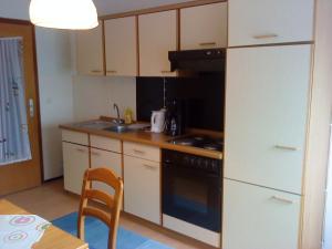 La cuisine est équipée de placards blancs et d'un four avec plaques de cuisson. dans l'établissement Gästehaus Burgwald-Trekking, à Mittelsimtshausen