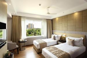 ein Hotelzimmer mit 2 Betten und einem Fenster in der Unterkunft Sugar Business Hotel in Kochi