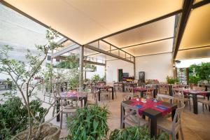 um restaurante com mesas, cadeiras e plantas em La Lanterna em Martano