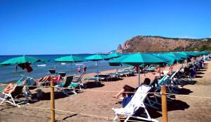 eine Gruppe von Menschen, die am Strand mit grünen Sonnenschirmen sitzen in der Unterkunft Villa Dei Principi Hotel in Terracina