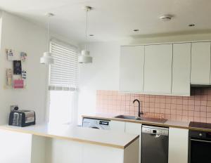 a kitchen with white cabinets and a counter top at Margate Holiday Apartment in Margate