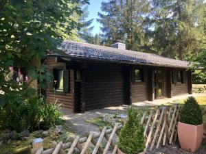 ein Blockhaus mit einem Zaun davor in der Unterkunft Wooden bungalow with oven, in Oberharz near a lake in Clausthal-Zellerfeld