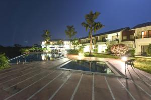 a swimming pool in front of a building at night at Regenta Resort Soma Vine Village Nashik in Nashik