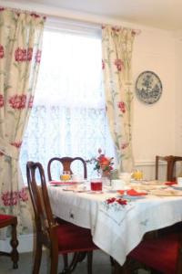 a dining room table with a white table cloth and a window at Knightsrest in Burnham on Sea