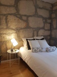 a bed in a room with a stone wall at Oporto Foz House close to the beach in Porto