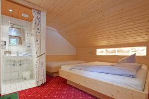 Schlafzimmer mit einem Bett, einer Dusche und einer Badewanne in der Unterkunft Pension Backstuba in Partenen