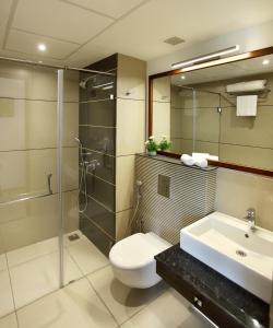 a bathroom with a toilet and a sink and a shower at Sugar Business Hotel in Cochin