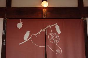 a curtain with a picture of a racket and leaves at 古民家ゲストハウス ナマケモノ in Ōno