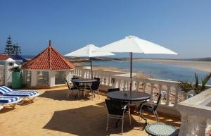 un patio con mesas y sillas y una playa en Villa Sur La Plage, en Oualidia