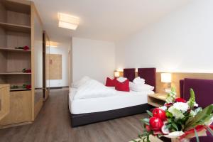 a hotel room with a white bed and red pillows at Hotel Sonnleiten in Ladis