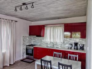 a kitchen with red cabinets and a table with chairs at Home by the sea in Monemvasia