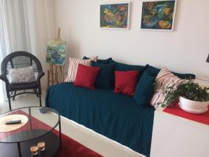 ein Wohnzimmer mit einem blauen Sofa und roten Kissen in der Unterkunft Harmony in Sveti Stefan