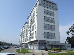a tall white building with cars parked in a parking lot at Apartament nad morzem, Gdańsk Zaspa in Gdańsk