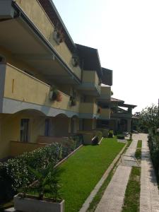 un edificio con un patio verde junto a un edificio en Residence Miralago Rooms & Apartments, en Manerba del Garda