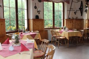 een eetkamer met tafels en stoelen met roze tafelkleden bij Hotel Waldfrieden in Elsterberg