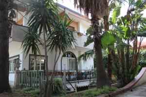 un bâtiment blanc avec des palmiers devant lui dans l'établissement Greenhouse, à Mascalucia