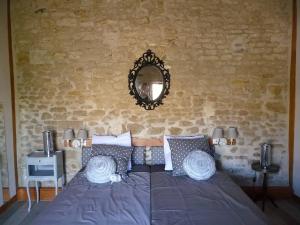 Schlafzimmer mit einem Bett und einem Spiegel an der Wand in der Unterkunft Le Haut Fontaine : minis maisons de charme in Saint-Georges-lès-Baillargeaux