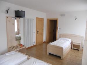 a bedroom with two beds and a tv on the wall at B&B Agritur Affittacamere Capra Mauro in Carzano