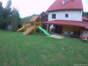 a backyard with a playground with a slide and a house at Domlesny in Kiczora