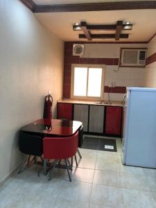 La cuisine est équipée d'une table, de chaises et d'un réfrigérateur. dans l'établissement Safwt Aldyar Furnished Units, à Abha