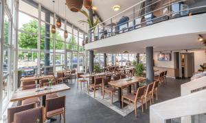 a restaurant with tables and chairs and large windows at Hotel am Fjord in Flensburg