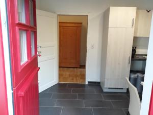 a hallway with a red door and a kitchen at Apartment am Park - Erica in Schneverdingen