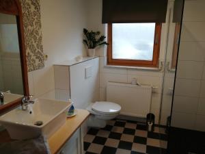 a bathroom with a sink and a toilet and a window at Apartment am Park - Erica in Schneverdingen