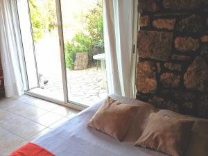 a bed with two pillows in a room with a window at Leucate,dans la verdure,studio caverne en pierre dans propriété sécurisée in Leucate