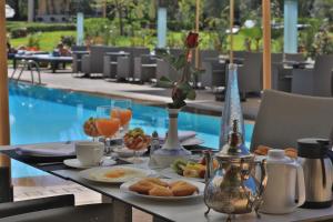 uma mesa com comida e bebidas ao pequeno-almoço e uma piscina em Palais Mehdi em Marrakech