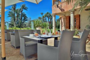 a table and chairs on a patio with palm trees at Palais Mehdi in Marrakech