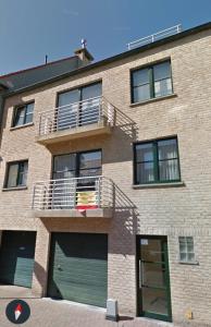 a brick building with a balcony and a garage at Duplex vernieuwd appartement Dujardin bubbelbad in Blankenberge