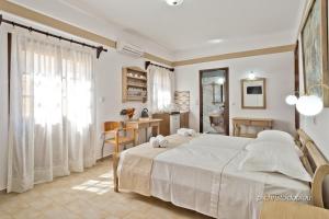 a bedroom with a large white bed and a kitchen at Philoxenia Studios 2 in Karpathos