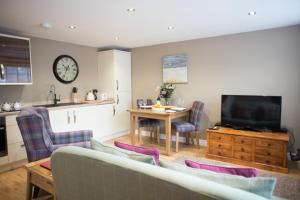 a living room with a couch and a table and a clock at Brewer's Cottage - Brosterfield Farm in Eyam