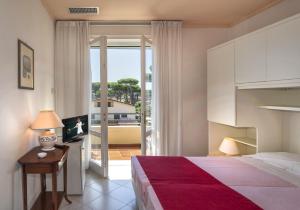 una camera con letto e porta di accesso a un balcone di Hotel Villa Edera a Marina di Pietrasanta