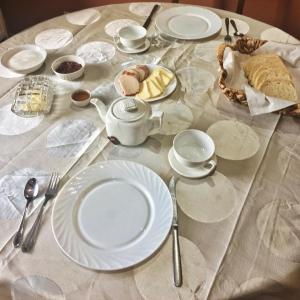 a table with white plates and utensils on it at Elizbar Talakvadze Winery in Kardanakhi