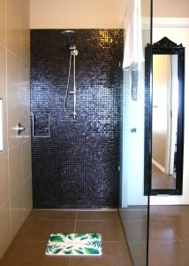 a bathroom with a shower with black tiles at Beautiful view house in Monbulk