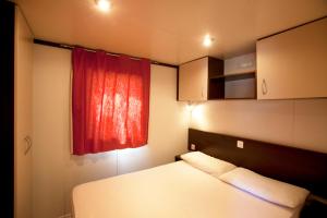 Camping Capalbio في كابالبيو: غرفة نوم بسرير ونافذة حمراء