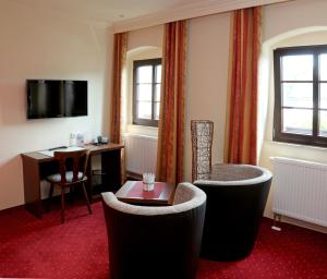 a hotel room with a table and chairs and a desk at Landhotel Thürmchen in Schirgiswalde