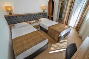 a hotel room with two beds and a mirror at Kleopatra Celine Hotel in Alanya