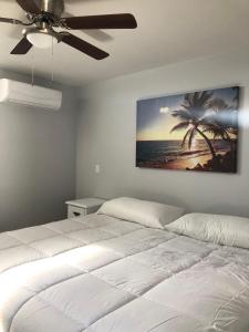 a bedroom with a white bed and a painting on the wall at Conjunto Ballena Townhouses in Puerto Peñasco