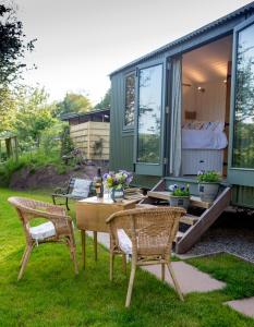 una casita verde pequeña con mesa y 2 sillas en GoldenValley Shepherd's Hut en Dorstone